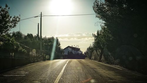 Empty road along trees and against sky