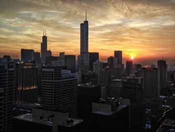 Modern buildings in city against sky during sunset