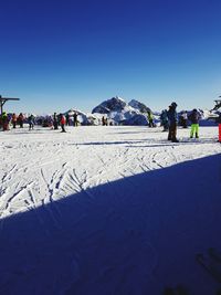 People on snowcapped mountain against clear blue sky