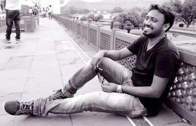 Young man looking away while sitting on wall