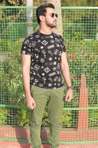 Young man looking away while standing in park