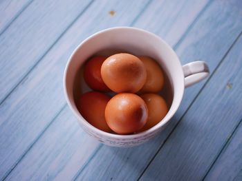 Fresh chicken eggs in a cup, on the wooden floor