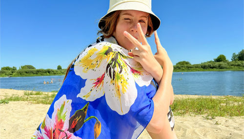 Portrait of young woman standing against sky