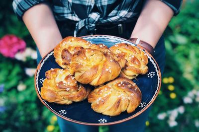 Midsection of woman hands holding baked pastry items in plate outdoors