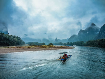 Man in boat on water against sky