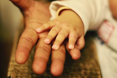 Close-up of father holding baby hand