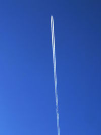 Low angle view of vapor trail against clear blue sky