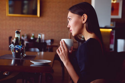 Side view of a young woman drinking coffee cup