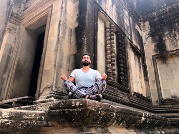 Full length of man doing yoga at historic building