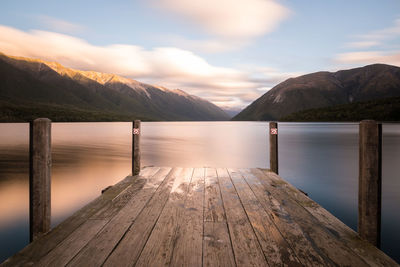 Wooden pier over lake against sky during sunset