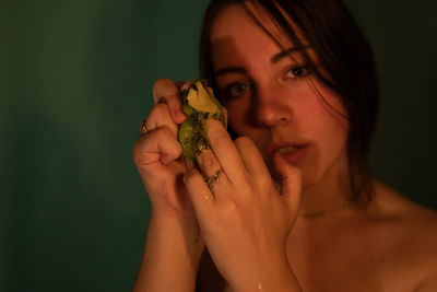 Close-up portrait of woman holding kiwi