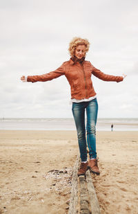 Smiling mid adult woman walking on wood at beach