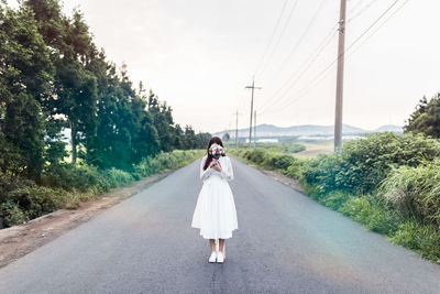 Portrait of woman on road against sky