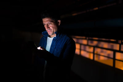 Mid adult man using mobile phone at night