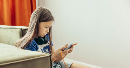 Side view of woman sitting on sofa at home