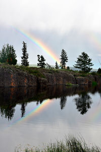 Scenic view of rainbow over lake against sky