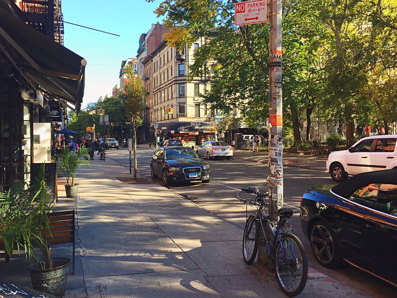 transportation, land vehicle, mode of transport, building exterior, car, street, architecture, built structure, city, parking, parked, stationary, bicycle, tree, road, city street, sunlight, the way forward, sidewalk, outdoors