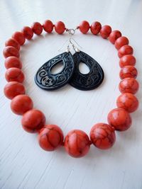 High angle view of orange beaded necklace with earrings on white table