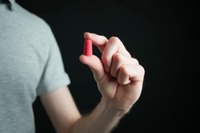 Midsection of woman holding cigarette against black background