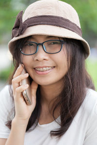 Close-up portrait of smiling young woman talking on phone