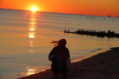 Silhouette woman walking at beach during sunset