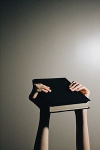 Cropped hand of woman using digital tablet against wall