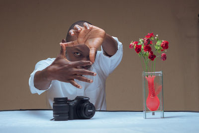 Rear view of boy holding flower on table against wall