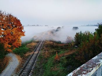 Railroad tracks during foggy weather against sky