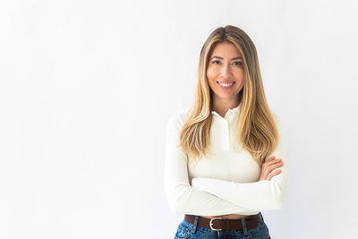 Portrait of young woman standing against white background