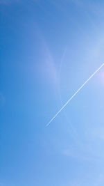 Low angle view of vapor trails in blue sky