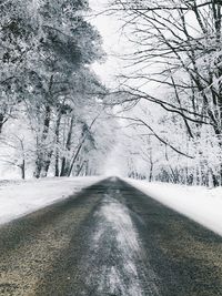 Road amidst snow covered trees during winter