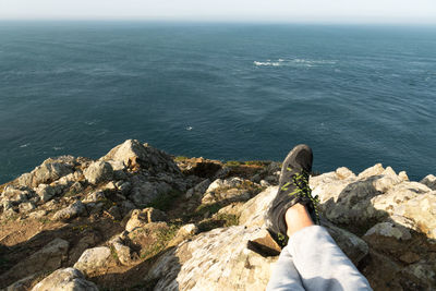 Low section of person on rock by sea