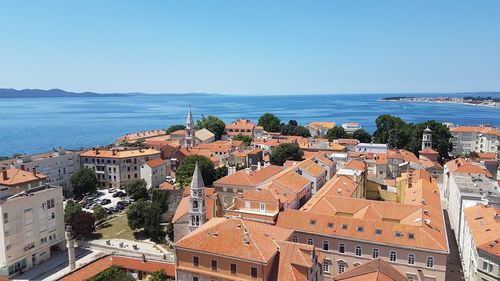 High angle view of townscape by sea against clear sky