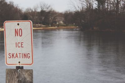 Information sign by lake against sky