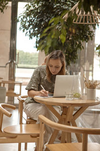 Young woman using laptop at outdoor cafe