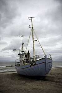 Ship moored on beach against sky