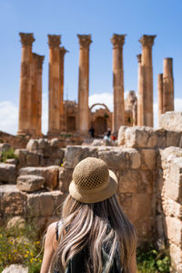 Rear view of woman standing against historic building