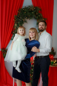Portrait of smiling woman standing against christmas tree