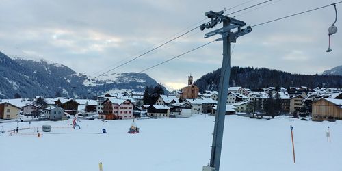 Overhead cable car on snow covered field against sky