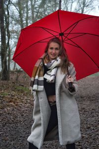 Portrait of young woman with umbrella standing in park