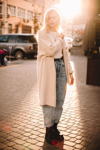 Hipster teenage girl standing on city street against sunlight