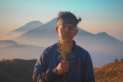 Portrait of young man wearing sunglasses against sky during sunset