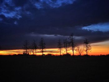 Silhouette trees on landscape against sky during sunset