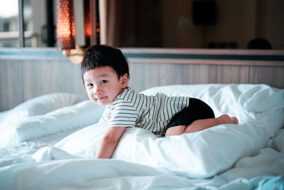 Baby boy kneeling on bed at home