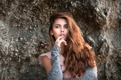 Thoughtful young woman with long hair by rock formation