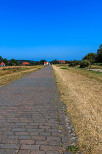 View of empty road against clear blue sky