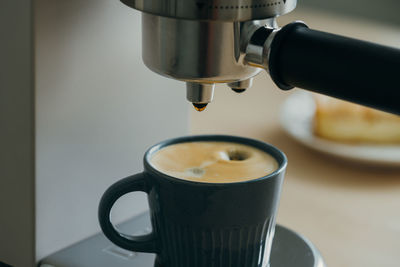 Morning ritual at breakfast with pouring coffee from coffee machine, drops of espresso dripping