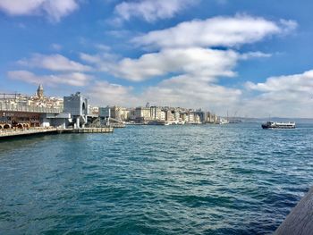 View of city at waterfront against cloudy sky