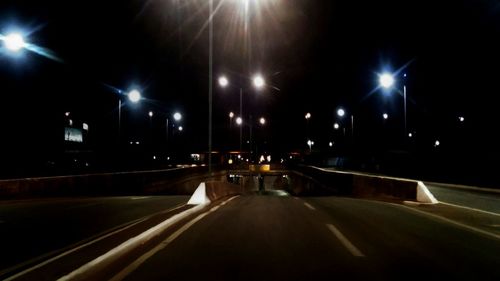 Empty road along illuminated street lights at night