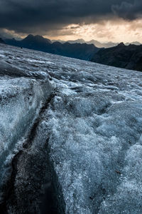 Frozen river against mountains during sunset